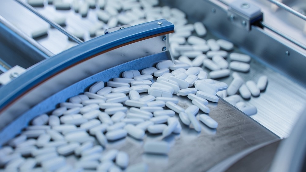Tablets and Capsules Manufacturing Process. Close-up Shot of Medical Drug Production Line. White Painkiller Pills are Moving on Conveyor at Modern Pharmaceutical Factory.